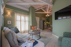 Ein Wohnzimmer mit Sofa, Couchtisch und Kamin. Es gibt einen Essbereich mit Tisch und Stühlen.