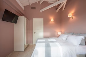 Ein Schlafzimmer mit einem Bett, einem an der Wand befestigten Fernseher und zwei Wandlampen.