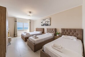 Een hotelkamer met twee bedden, een groot raam met gordijnen, een hoofdbord en een schilderij aan de muur.
