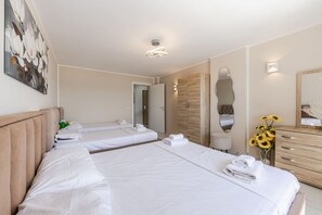 Een hotelkamer met twee bedden, een houten dressoir, een spiegel en een schilderij aan de muur.