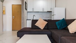 A modern living room with a sofa, a coffee table, and a kitchen area in the background. - Sun Sea Apartment Durr s Waterfront (Durrës)