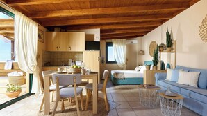 Teto de madeira, área de jantar com mesa e cadeiras, um sofá e uma pequena cozinha.