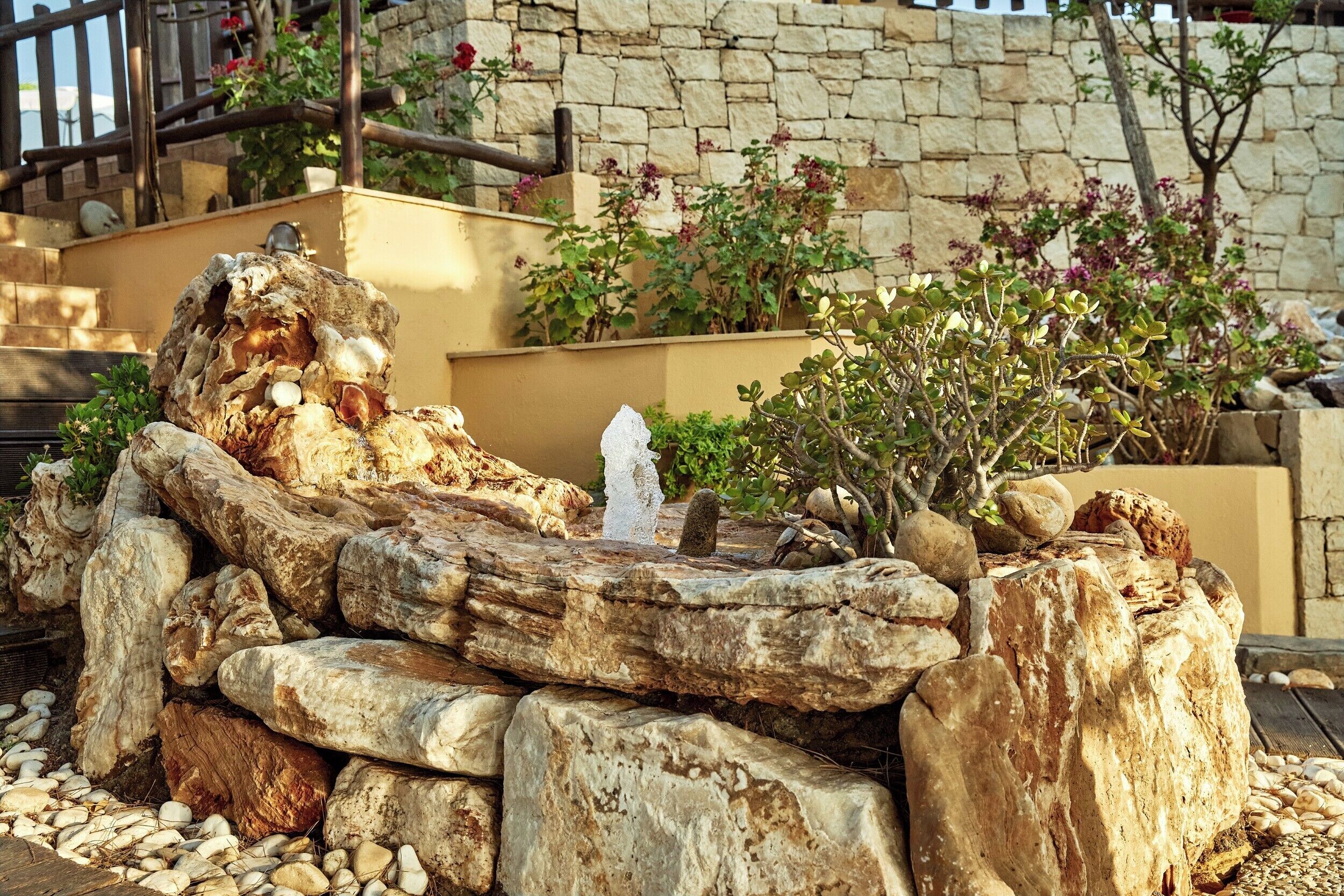A stone wall with plants and a wooden structure.