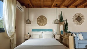 Quarto com cama, mesas de cabeceira, um sofá azul, arte decorativa nas paredes e plantas em vasos.