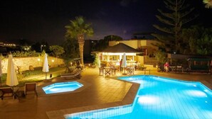 Piscina com área rebaixada, espaço para assentos ao ar livre e bar.
