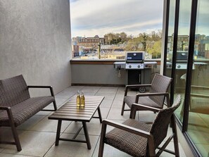 A balcony with wicker furniture, a grill, and bottles on a table. - South Slope View with private 2 car garage, pet friendly, private elevator (Asheville)