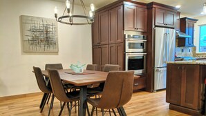 Een moderne keuken met houten kastjes, een eettafel met stoelen en ingebouwde apparatuur.
