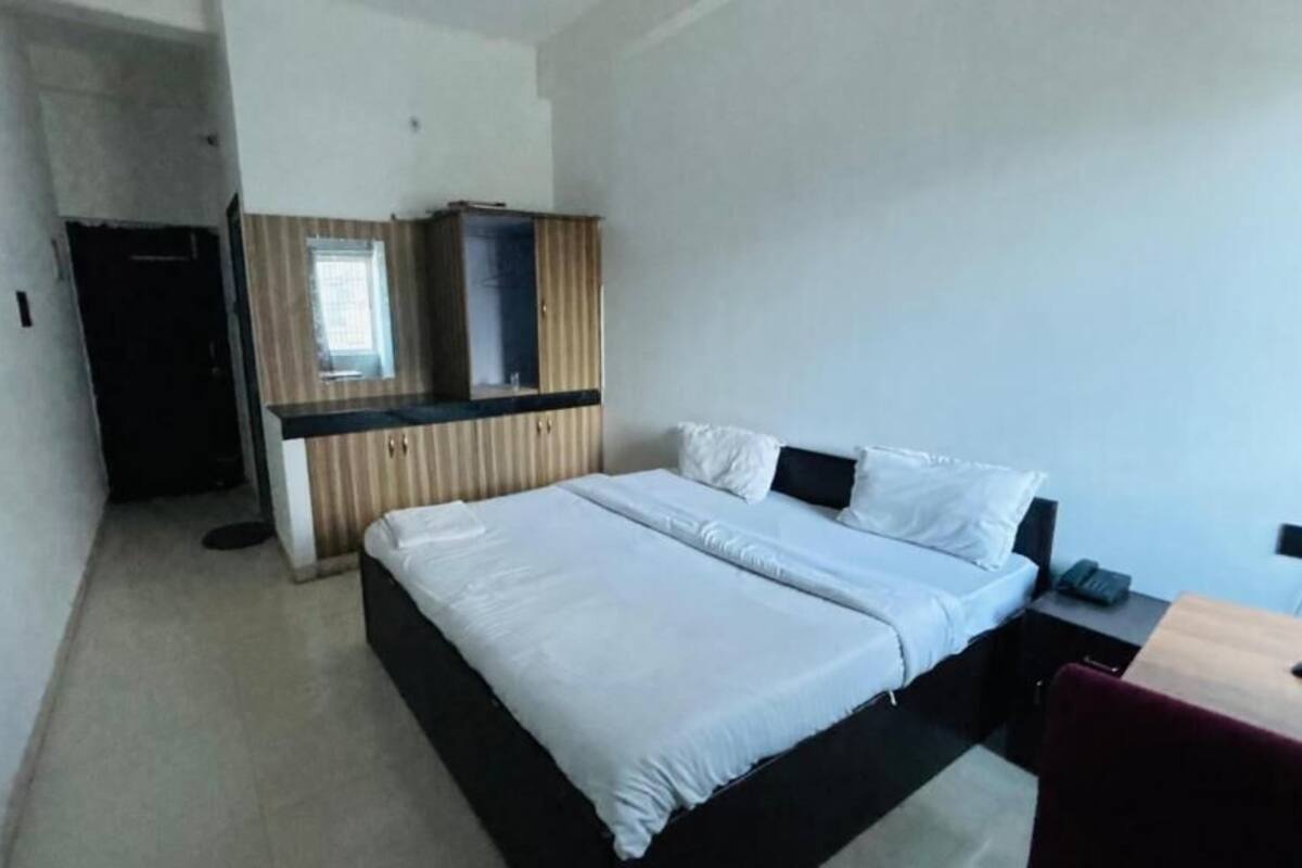 Quarto de hotel com cama, escrivaninha, guarda-roupa e espelho.