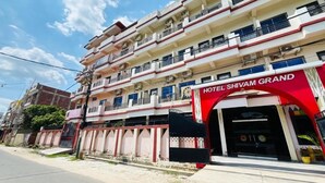 Un hotel de varios pisos con una fachada llamativa de rojo y blanco, balcones y una entrada con portón.