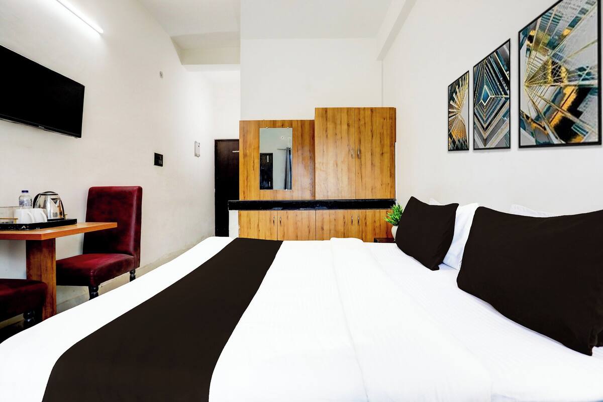 Quarto de hotel com cama, secretária com cadeira, televisão e obras de arte na parede.