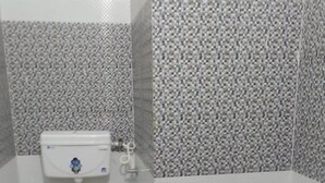 Un baño pequeño con inodoro, ducha y un balde.
