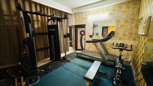 Un gimnasio con cinta de correr, banco para pesas y diversas máquinas de ejercicio.