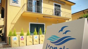 Un edificio amarillo con un letrero que dice 'L'onda' y un logotipo con una ola y pájaros.
