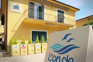 A yellow building with a sign reading 'L'onda' and a logo featuring a wave and birds. - Apartment Fezzano di Portovenere L'ONDA 1 (Fezzano di Portovenere)