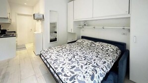 Un dormitorio con cama, armario empotrado y una pequeña kitchenette.