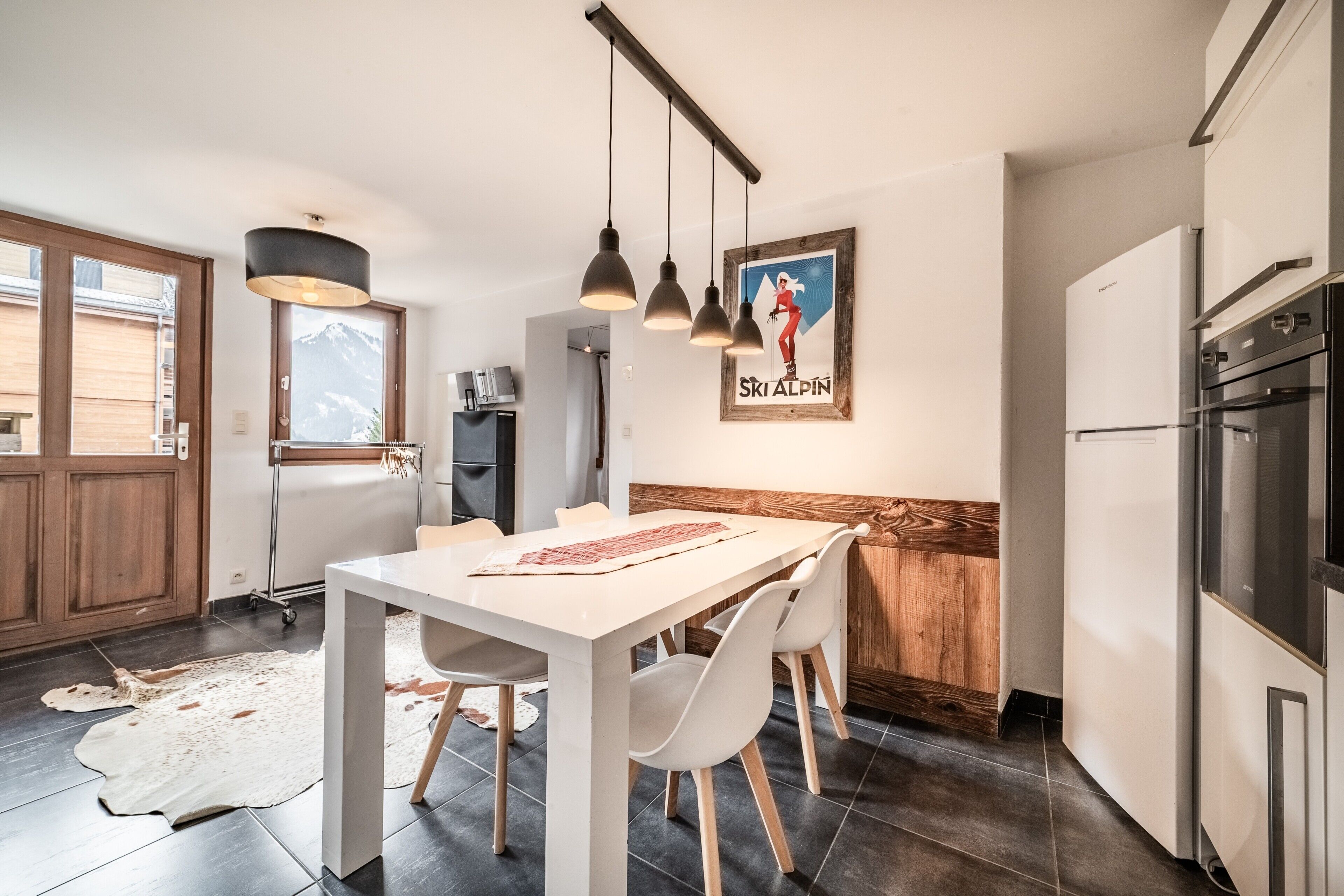 Una cocina moderna con comedor, detalles de madera y vistas a la montaña.