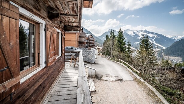 Eine Holzhütte mit einem Balkon und Blick auf eine Berglandschaft.