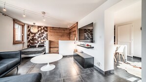 Ein modernes Wohnzimmer mit einer Couch, einem runden Couchtisch und einem an der Wand montierten Fernseher.