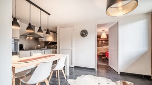 Eine moderne Küche mit Pendelleuchten, ein Essbereich mit Stühlen, einem Teppich und einer Uhr an der Wand.