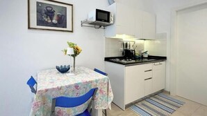 Une petite cuisine équipée d’un four à micro-ondes, d’un évier et d’une table avec des chaises.