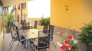 Eine Terrasse im Freien mit Tisch und Stühlen, umgeben von Blumentöpfen und Blumen.