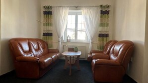 A room with two leather armchairs and a small round table, a window with curtains, and a radiator. - Pezion and apartman near Karlovy Vary (Chodov)