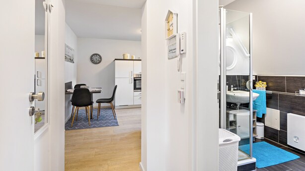 A modern hotel room with a kitchenette, a bathroom with a shower, and a dining area with a table and chairs. - Modern Apartment – Quiet & Prime Location in Neheim (Arnsberg)