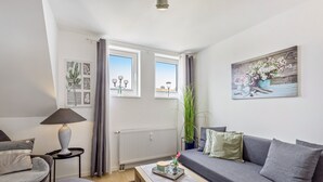 A modern living room with a grey sofa, a wooden coffee table, a lamp, and a painting on the wall. - Modern Apartment – Quiet & Prime Location in Neheim (Arnsberg)