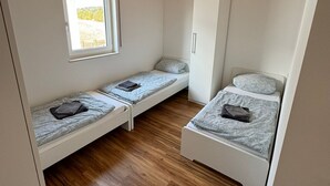 Ein kleines Zimmer mit zwei Etagenbetten, einem Kleiderschrank, einem Fenster und Holzboden.