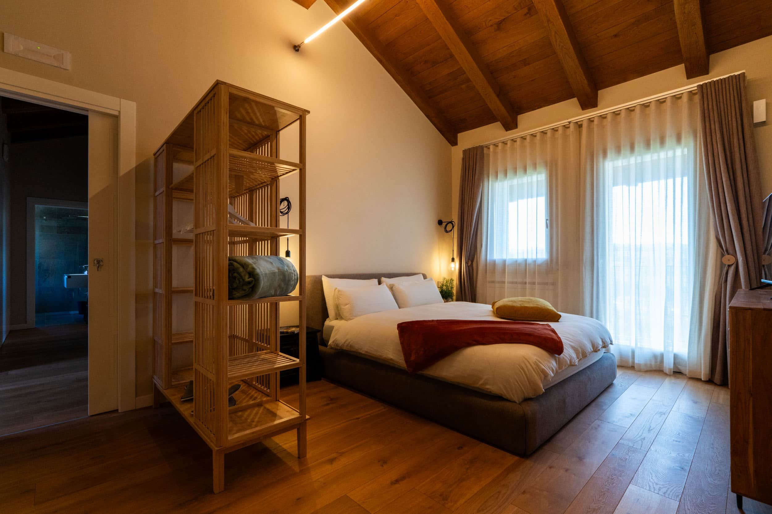 Ein Schlafzimmer mit einem Bett, einem Holzbücherregal und einer Holzzieldecke.