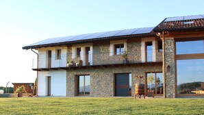 A two-story house with a stone facade, large windows, and a balcony. - Junior Suite with SPA & Pool (Dogliani)