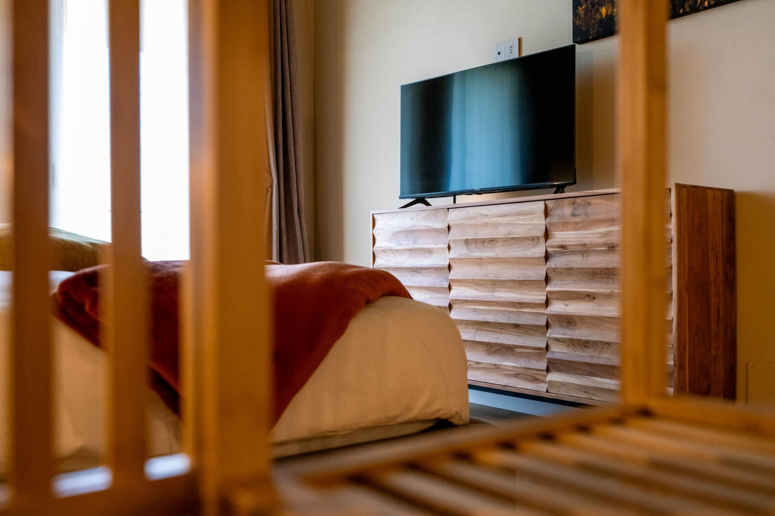Una camera da letto con un letto, una televisione su una cassettiera in legno e una finestra con tende.