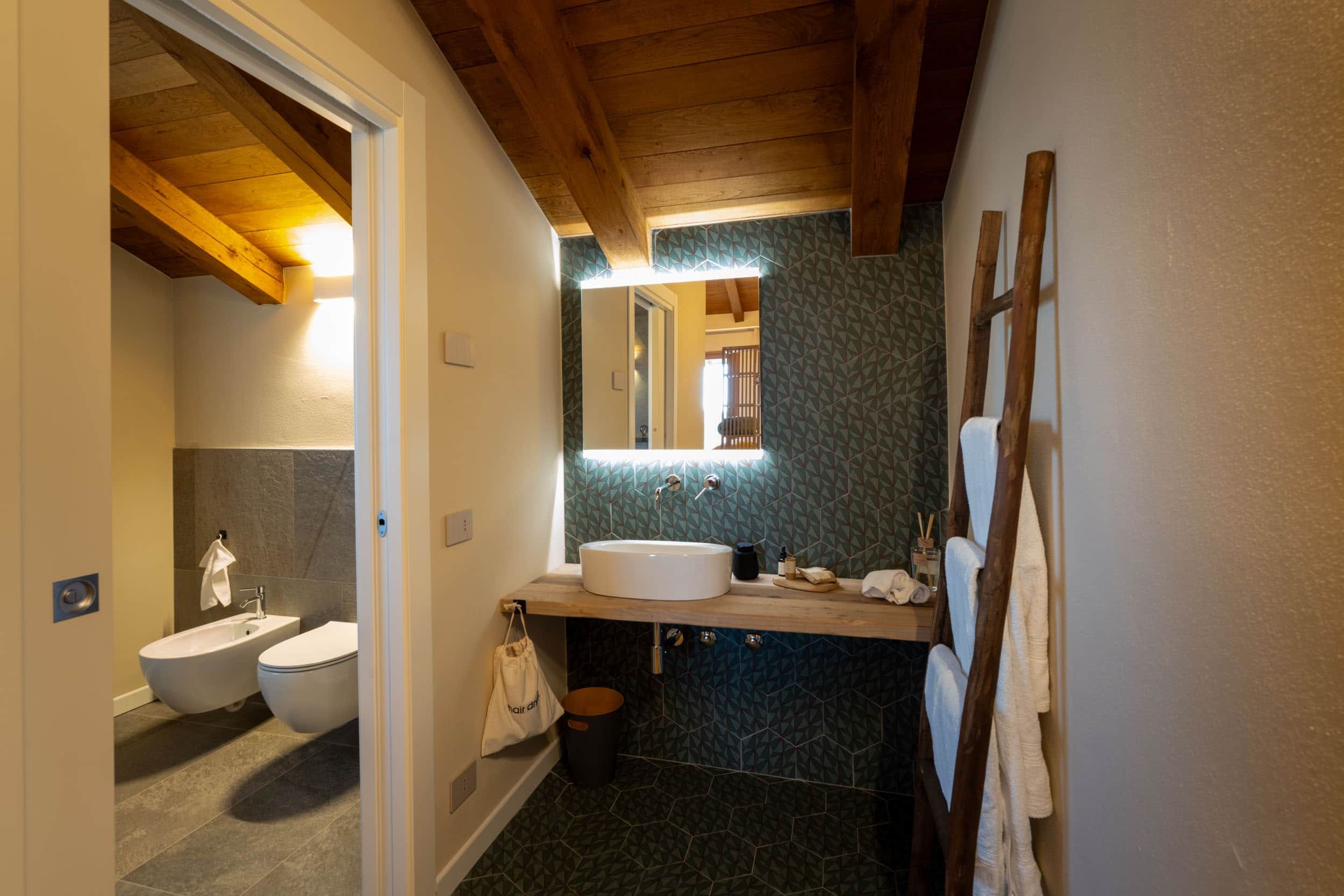 Un bagno con soffitto in legno, un lavandino, un bidet e uno specchio.