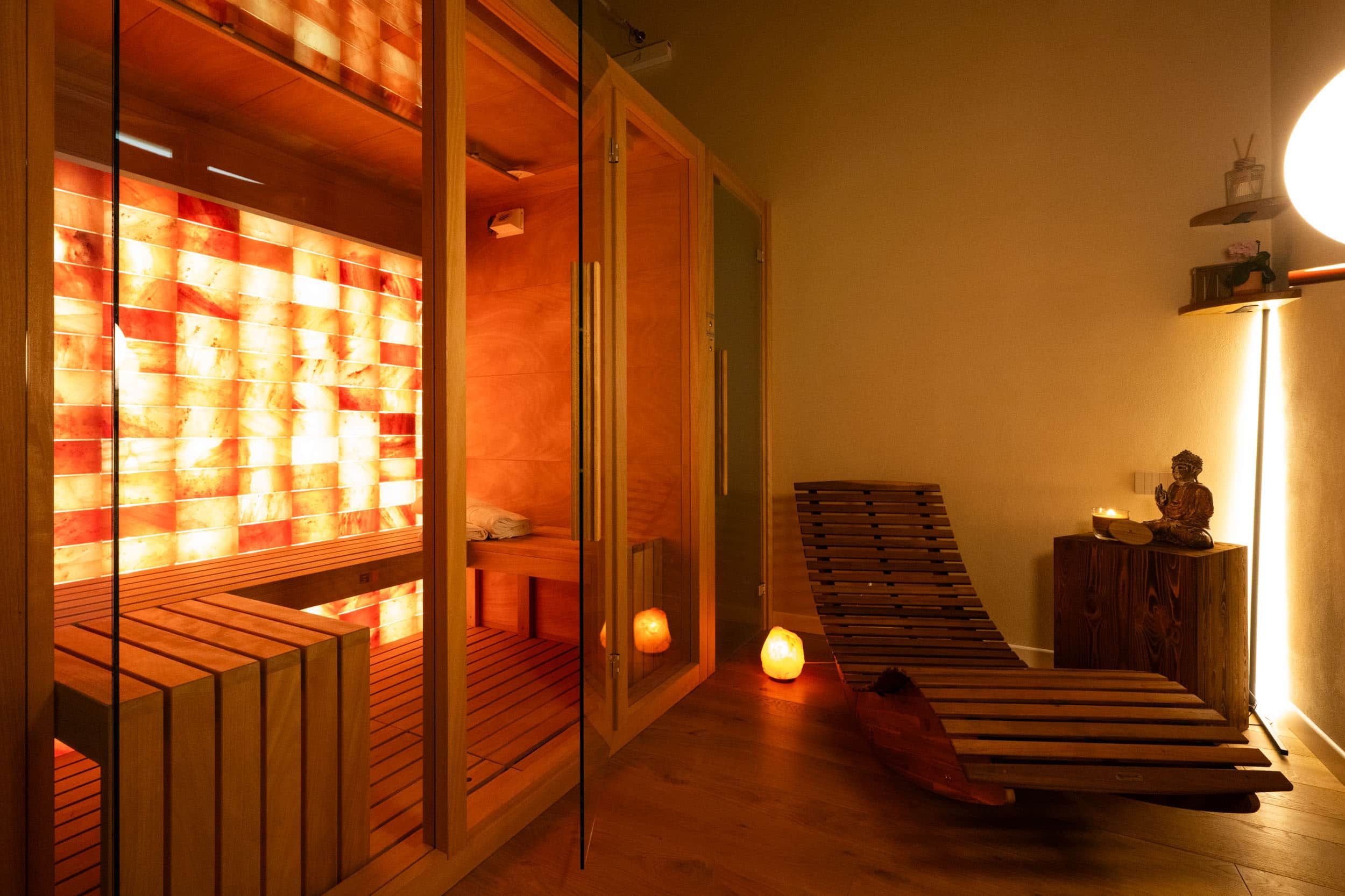 Eine Holzsauna mit Bänken und einer Glastrennwand, einer kleinen Statue und einer Holzbank an der Wand.