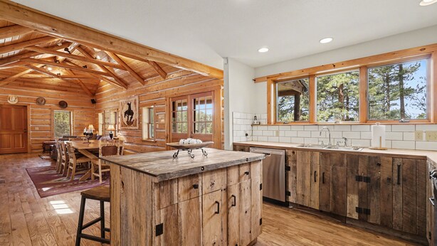A spacious kitchen with wooden cabinetry, a large island, and a view of the outdoors through large windows. - Historical Crocker Ranch - Rowe House 23-zone3423 3 Bedroom Home (Drake)