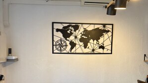 A room with a grey sofa, a world map artwork, a ceiling light, and an air conditioning unit.