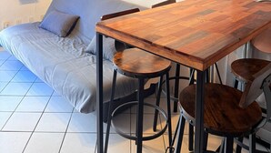 A modern living space with a wooden dining table, bar stools, a grey sofa, and a world map artwork on the wall.