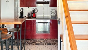 A kitchen with a wooden staircase, a clock, and a tiled floor.