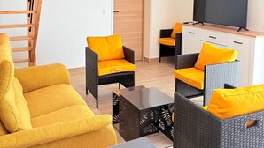 A furnished living room with a sofa, chairs, a coffee table, a TV, and a wooden ladder. - St Cyprien, charming house and beautiful sunny exterior (Saint-Cyprien)