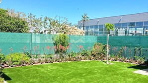 A well-maintained lawn with a green fence, a palm tree, and a building with 'BENETEAU' visible in the background. - St Cyprien, charming house and beautiful sunny exterior (Saint-Cyprien)