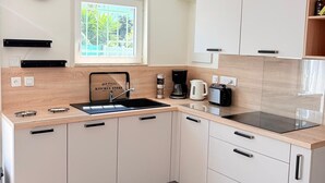 A modern kitchen with a built-in stove, sink, and a window with a view of greenery. - St Cyprien, charming house and beautiful sunny exterior (Saint-Cyprien)