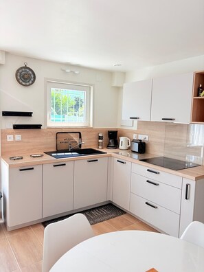 A modern kitchen with a built-in stove, sink, and a window with a view of greenery. - St Cyprien, charming house and beautiful sunny exterior (Saint-Cyprien)