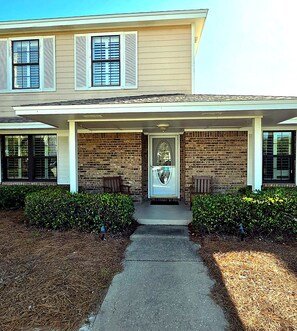 A two-story building with a covered front porch, brick walls, and a central door. - Coastal Retreat with Private Beach Access less than 50ft from home (Miramar Beach)