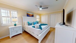 A bedroom with a bed, nightstand, lamp, TV, and wardrobe. - Coastal Retreat with Private Beach Access less than 50ft from home (Miramar Beach)