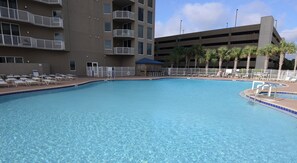Una piscina con sillas de descanso y un edificio al fondo.