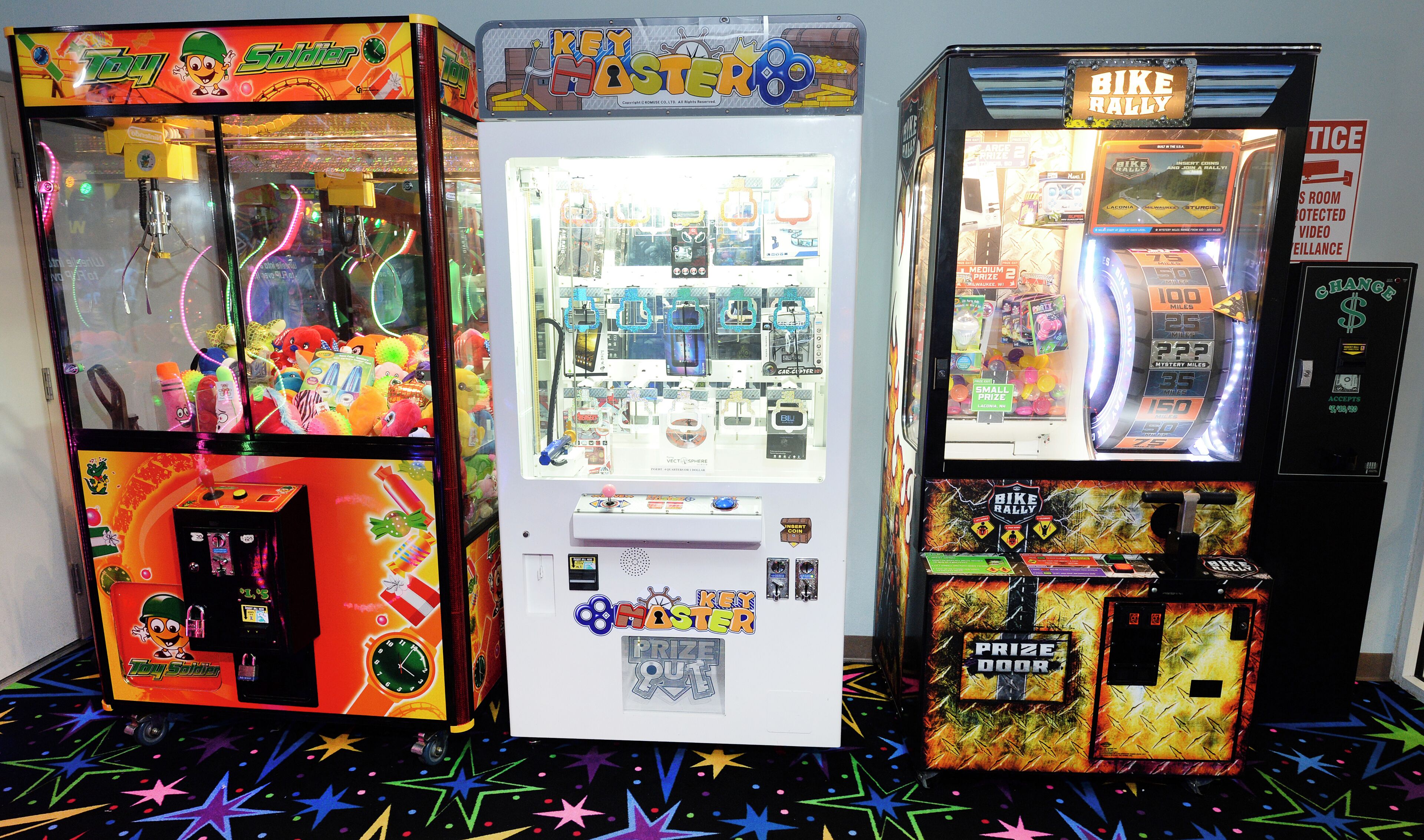 Tres máquinas de juegos con puertas de premios, un reloj y una zona pequeña para los premios.