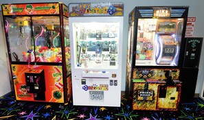 Tres máquinas de juegos con puertas de premios, un reloj y una zona pequeña para los premios.
