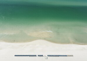 Una playa con una fila de sillas azules y una zona arenosa.