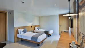 Una habitación de hotel moderna con dos camas, un cabecero de madera, un escritorio y un ventanal grande.