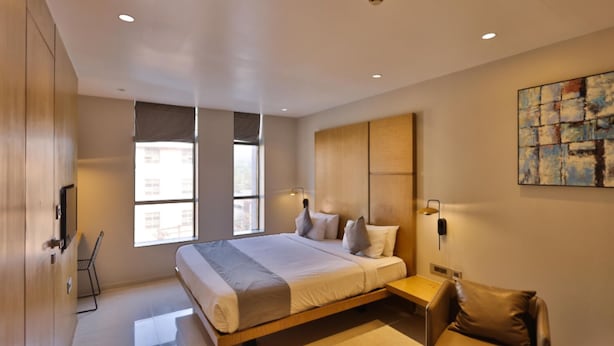 Una habitación de hotel moderna con una cama grande, un escritorio y una silla.